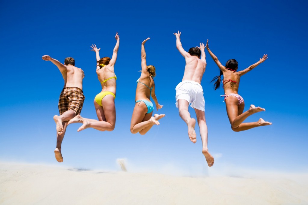 Portrait of jumping young people a backs on the beach